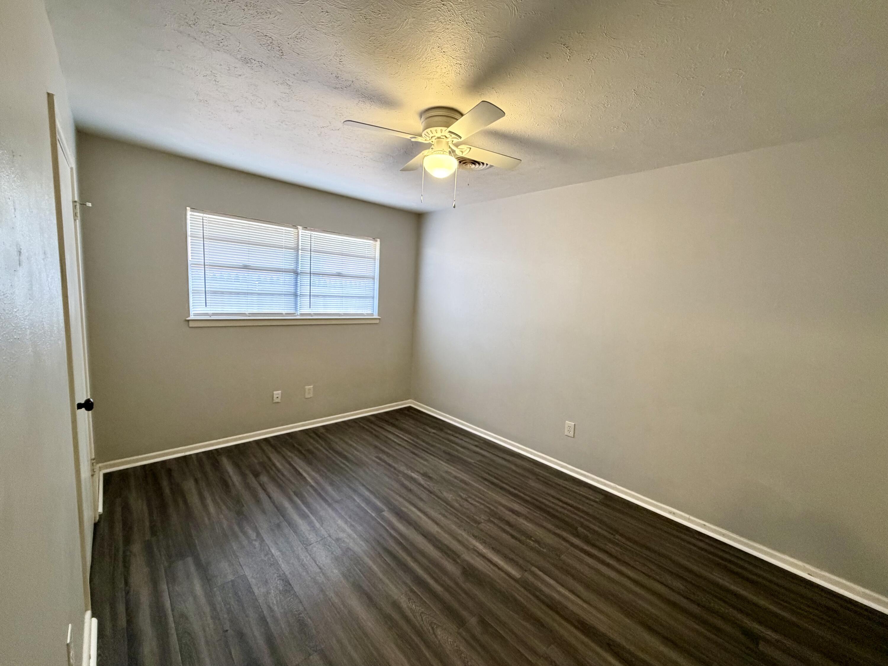 3813 51st Street, Unit A Lubbock, TX 79413 - Photo 14 of 17 an empty room with a window and wooden floor