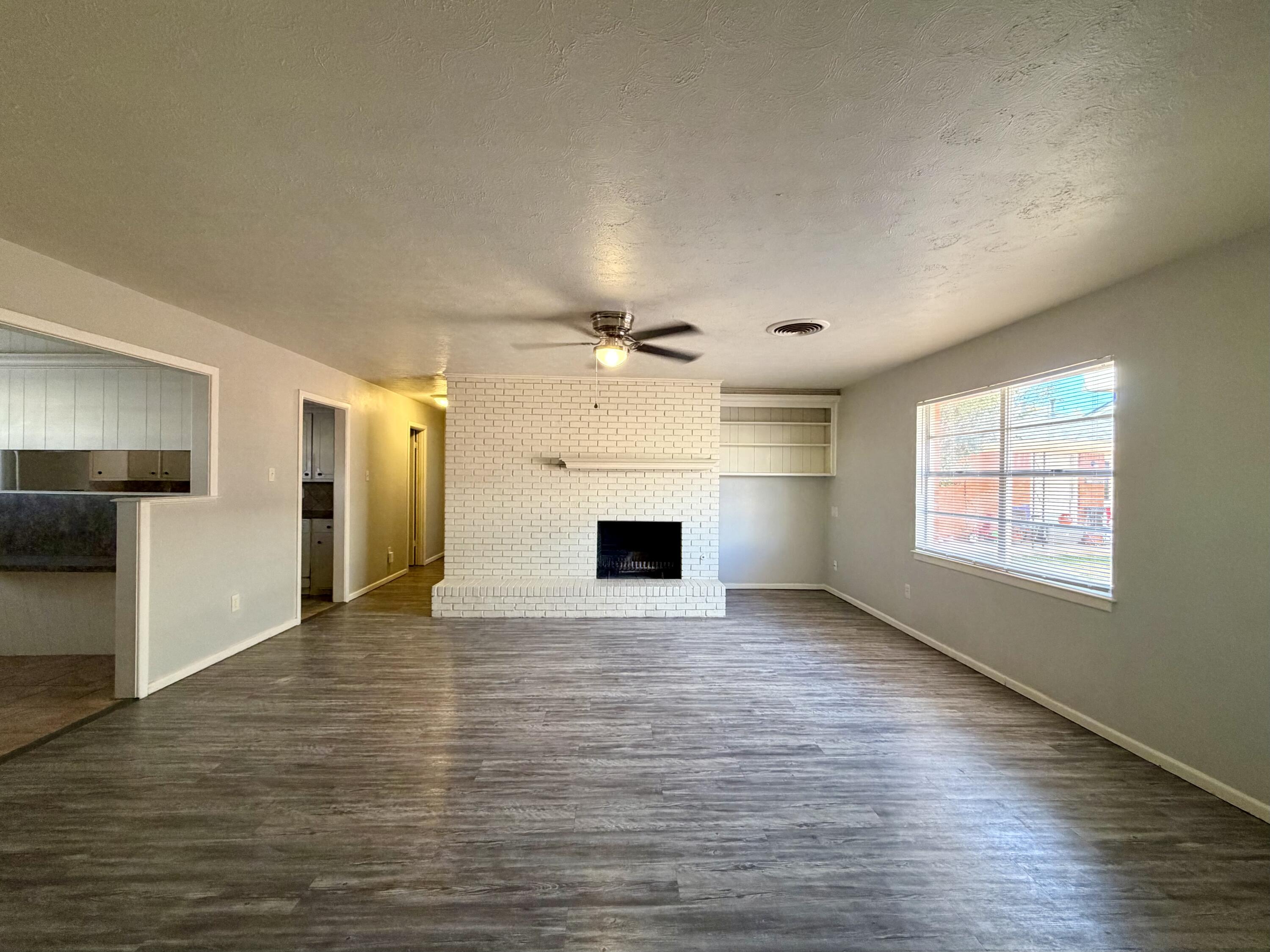 3813 51st Street, Unit A Lubbock, TX 79413 - Photo 3 of 17 wooden floor in an empty room with a window