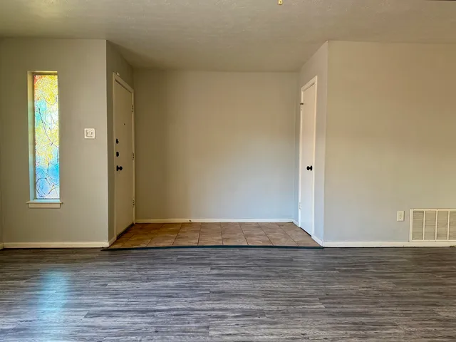 a view of a livingroom with wooden floor and kitchen