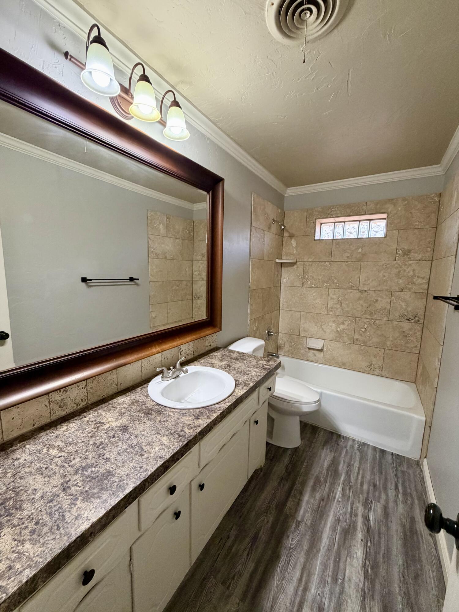 3813 51st Street, Unit A Lubbock, TX 79413 - Photo 9 of 17 a bathroom with a granite countertop sink a toilet and bathtub