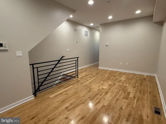 an empty room with wooden floor and stairs