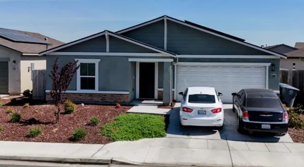 a front view of a house with cars parked
