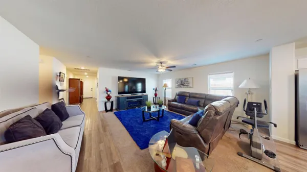 a living room with furniture a flat screen tv and kitchen view