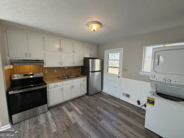 a kitchen with granite countertop a refrigerator stove and sink