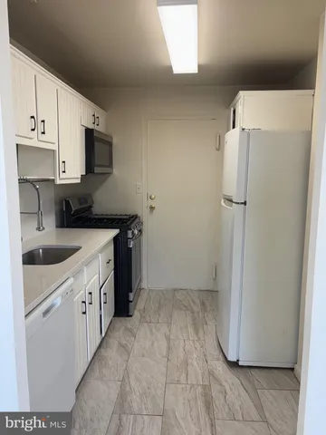 a kitchen with a sink a refrigerator a microwave and cabinets