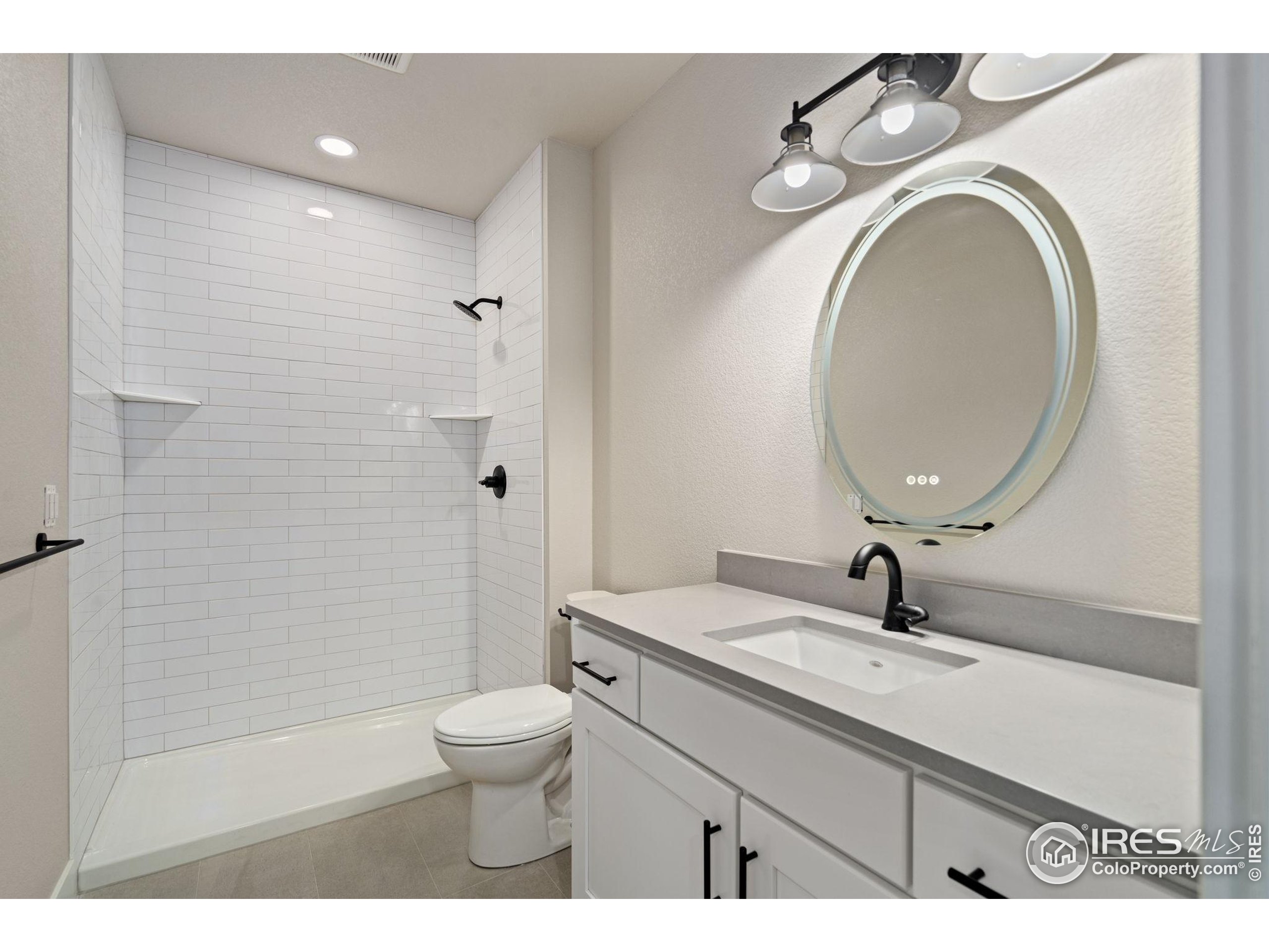 1369 Burt Avenue Berthoud, CO 80513 - Photo 36 of 41 a bathroom with a toilet a sink a mirror and vanity