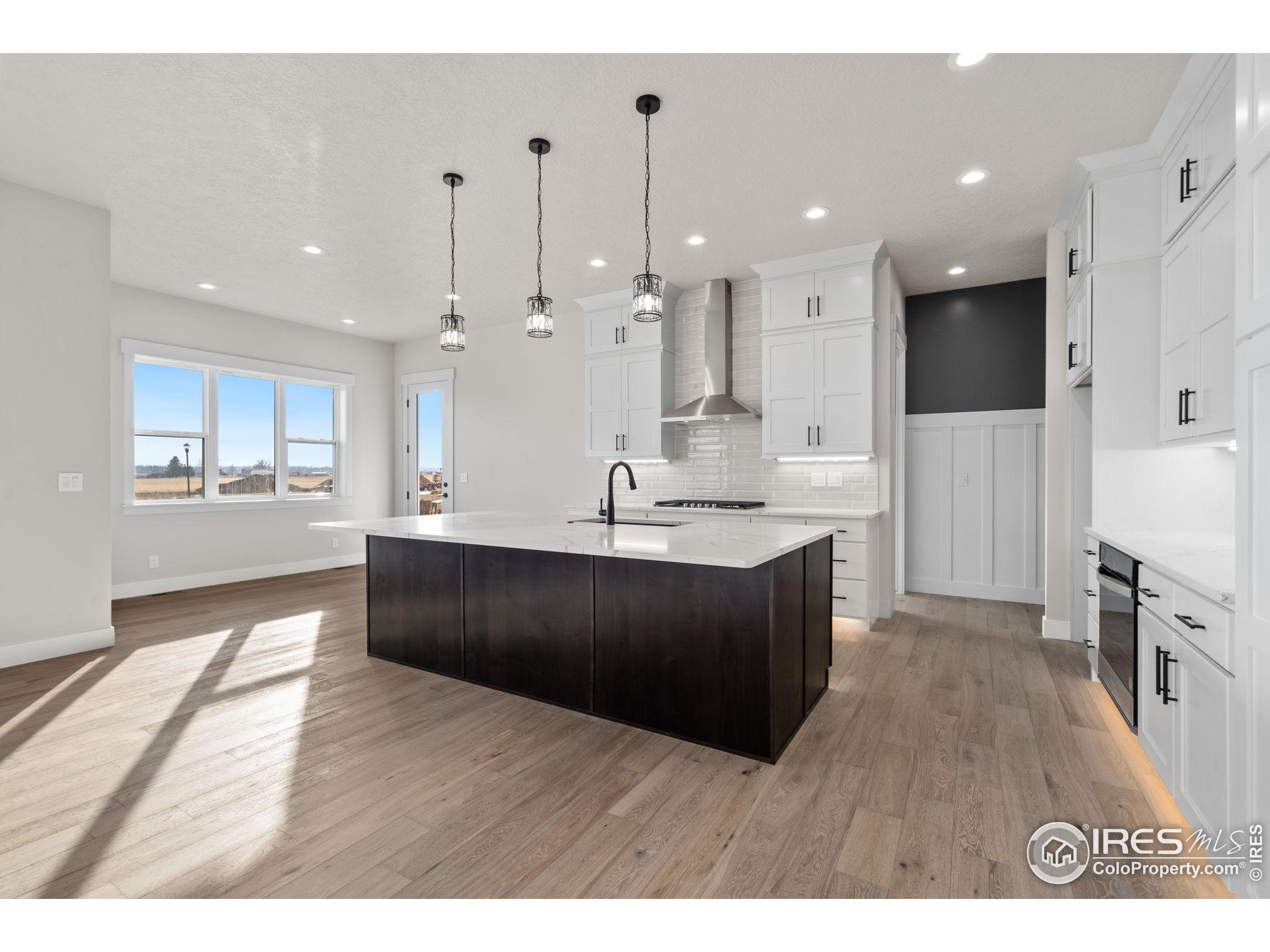 1369 Burt Avenue Berthoud, CO 80513 - Photo 6 of 41 a large kitchen with stainless steel appliances kitchen island a large counter top and a wooden floor