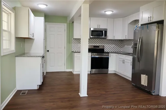 a kitchen with granite countertop a refrigerator stove top oven and sink