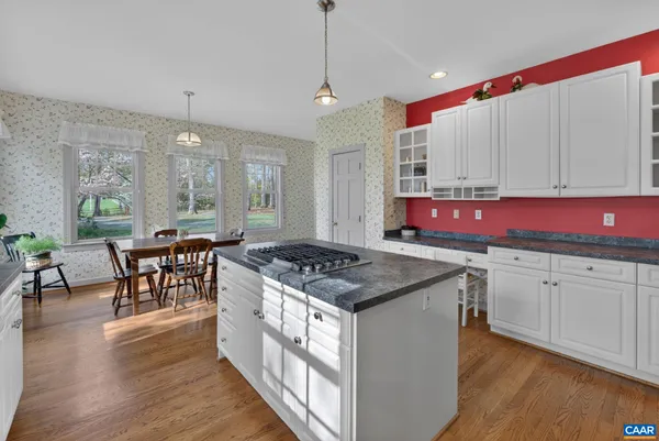 a kitchen with stainless steel appliances granite countertop a stove a sink dishwasher and white cabinets with wooden floor