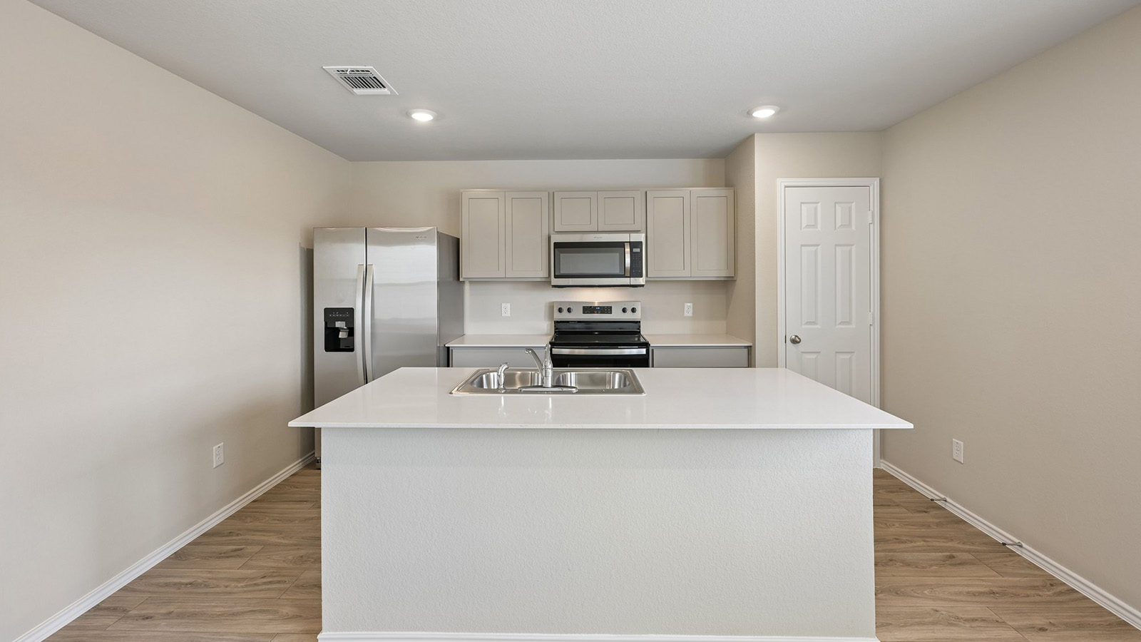 A spacious kitchen island overlooks the cooking area with modern finishes and durable hard surface floors.