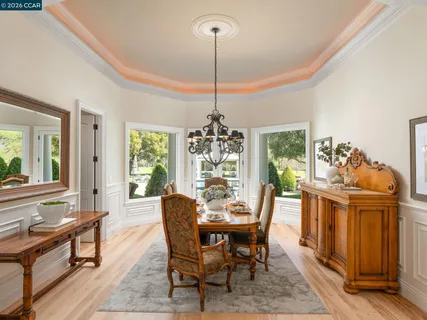 a kitchen with stainless steel appliances kitchen island granite countertop a dining table chairs and white cabinets