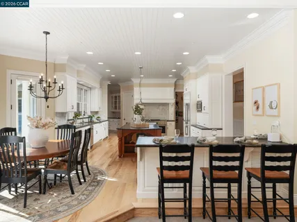 a kitchen with stainless steel appliances kitchen island granite countertop a dining table chairs and white cabinets