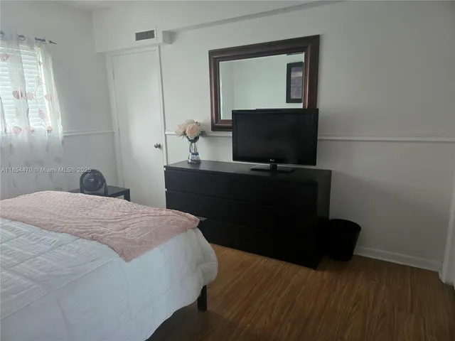 a bedroom with a bed and a flat tv screen on a dresser
