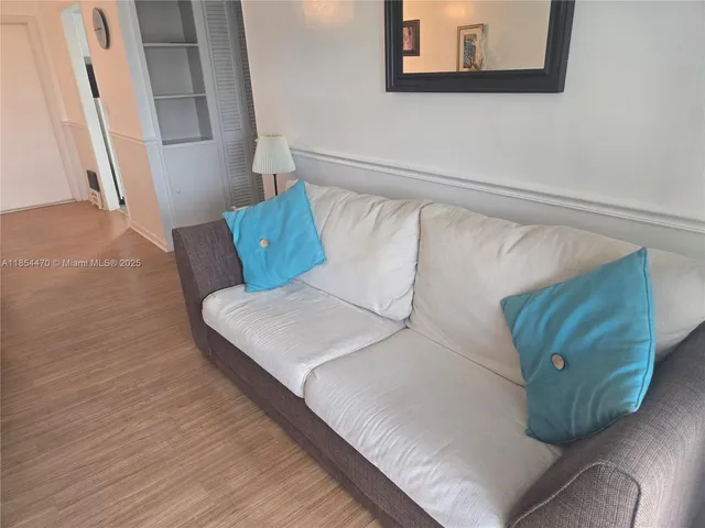 a living room with couches and kitchen view with wooden floor