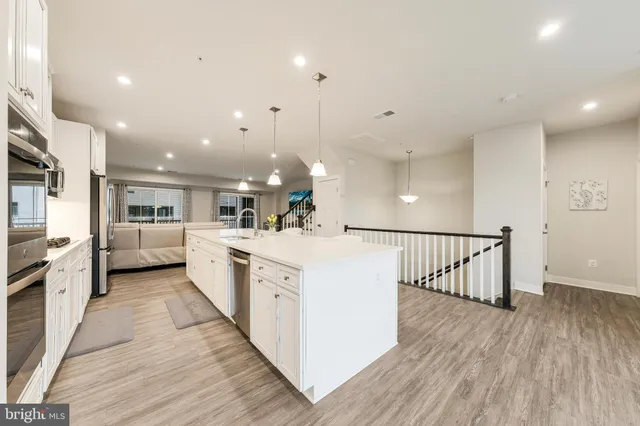 a large white kitchen with kitchen island a stove a sink a refrigerator and cabinets