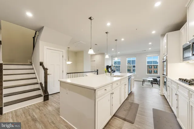 a large kitchen with stainless steel appliances kitchen island a large counter top a sink a stove and a refrigerator