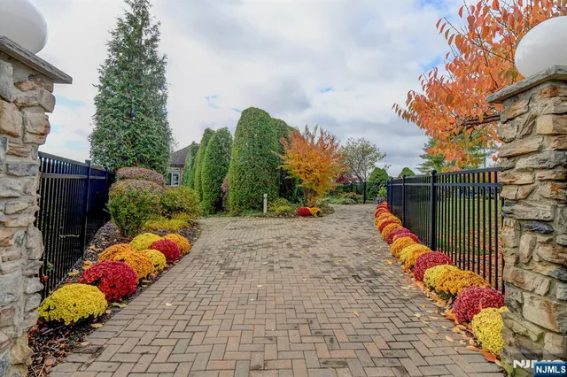 a view of a pathway with a bunch of flower plants and wooden fence