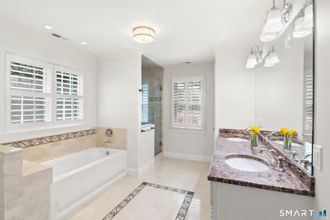 a bathroom with a granite countertop sink a bathtub and a window