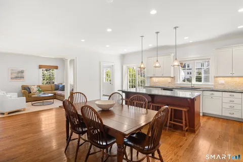 a dining room with stainless steel appliances granite countertop a table chairs and a living room