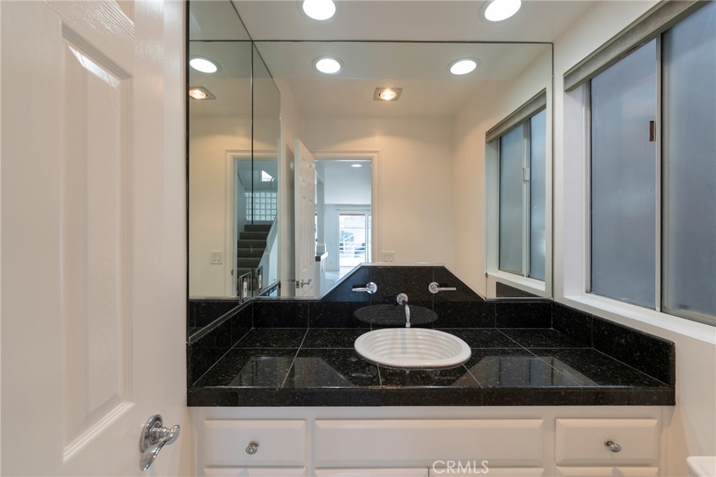 3310 Tempe Drive Huntington Beach, CA 92649 - Photo 18 of 52 a bathroom with a granite countertop sink a mirror and shower