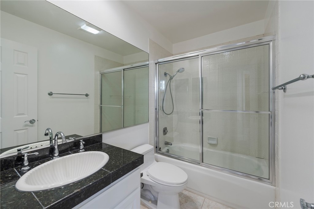 3310 Tempe Drive Huntington Beach, CA 92649 - Photo 32 of 52 a bathroom with a granite countertop sink toilet a mirror and shower