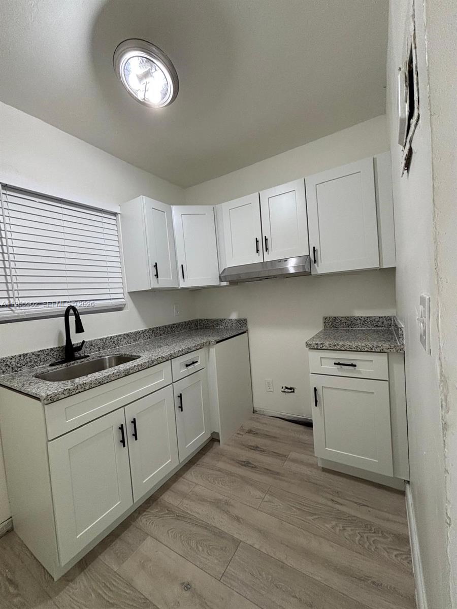 a kitchen with granite countertop a sink stainless steel appliances and cabinets