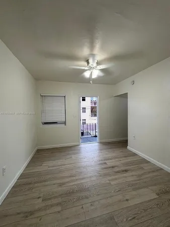 an empty room with wooden floor chandelier fan and windows