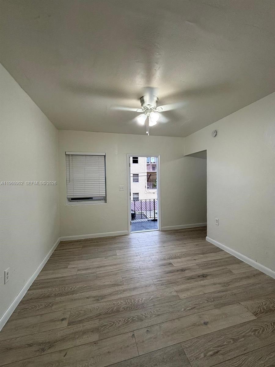 200 Northwest 13th Street, Unit 5 Miami, FL 33136 - Photo 3 of 9 an empty room with wooden floor chandelier fan and windows