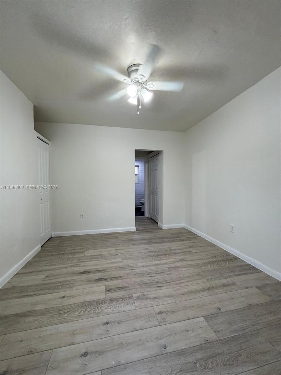 200 Northwest 13th Street, Unit 5 Miami, FL 33136 - Photo 8 of 9 a view of an empty room with wooden floor and a ceiling fan