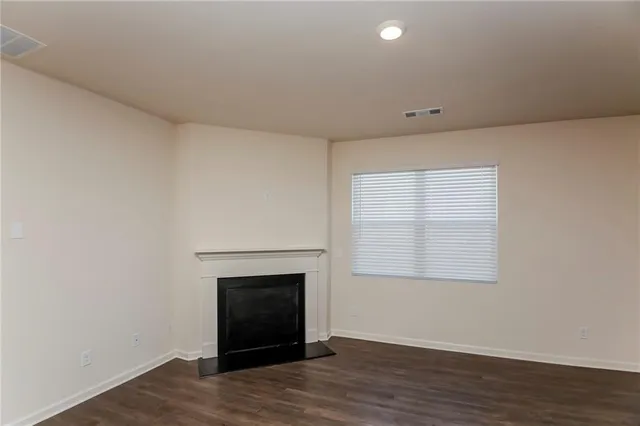 an empty room with wooden floor a exposed radiator and a window