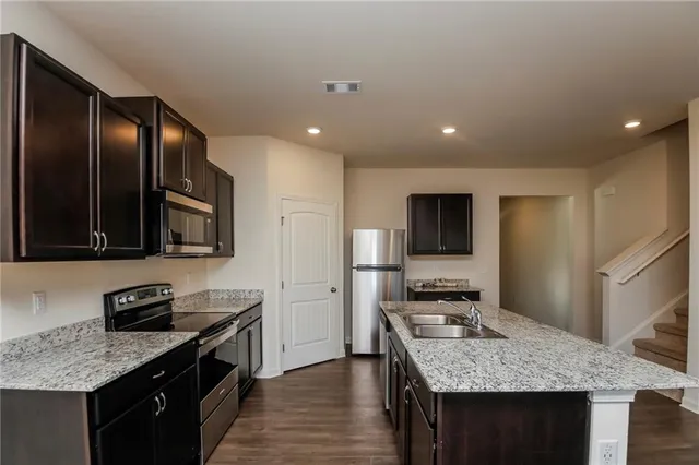 a kitchen with stainless steel appliances granite countertop a sink stove and refrigerator