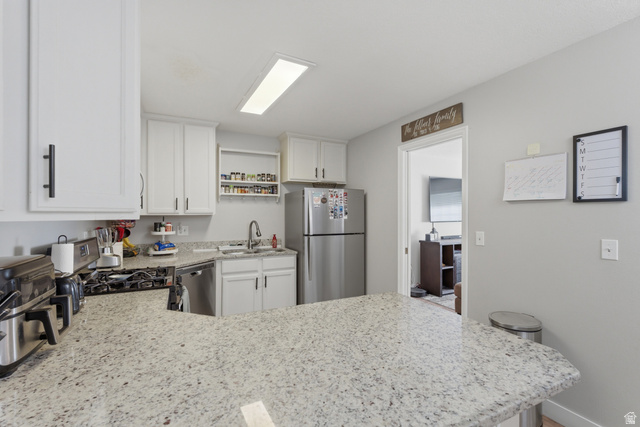 282 West 960 South, Unit C Provo, UT 84601 - Photo 7 of 33 Kitchen with stainless steel appliances, a peninsula, white cabinetry, and light stone counters