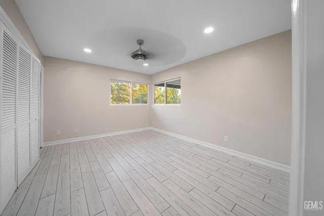 an empty room with wooden floor and a ceiling fan