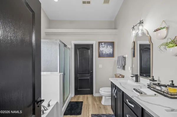 a bathroom with a double vanity sink a toilet and shower