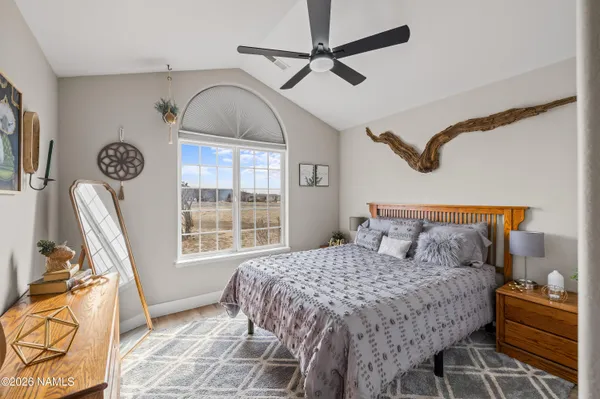 a bedroom with a bed next to a window and a flat tv screen
