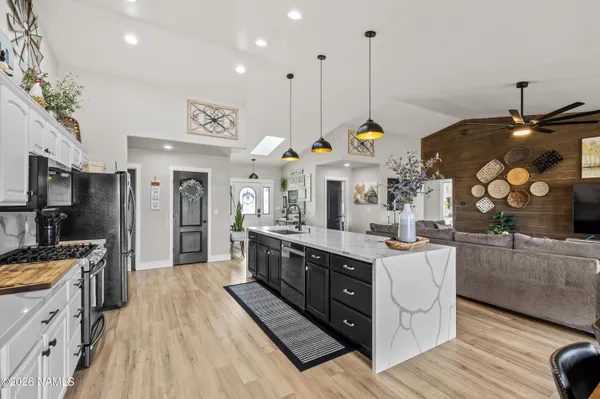a kitchen with stainless steel appliances granite countertop a sink a stove and a wooden floors