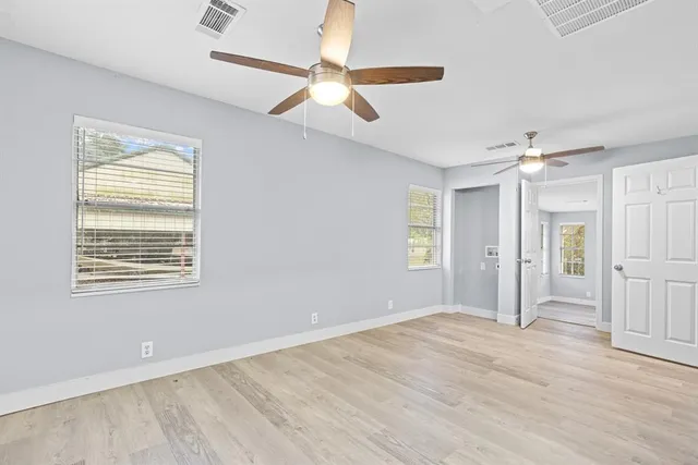 a view of empty room with wooden floor and fan