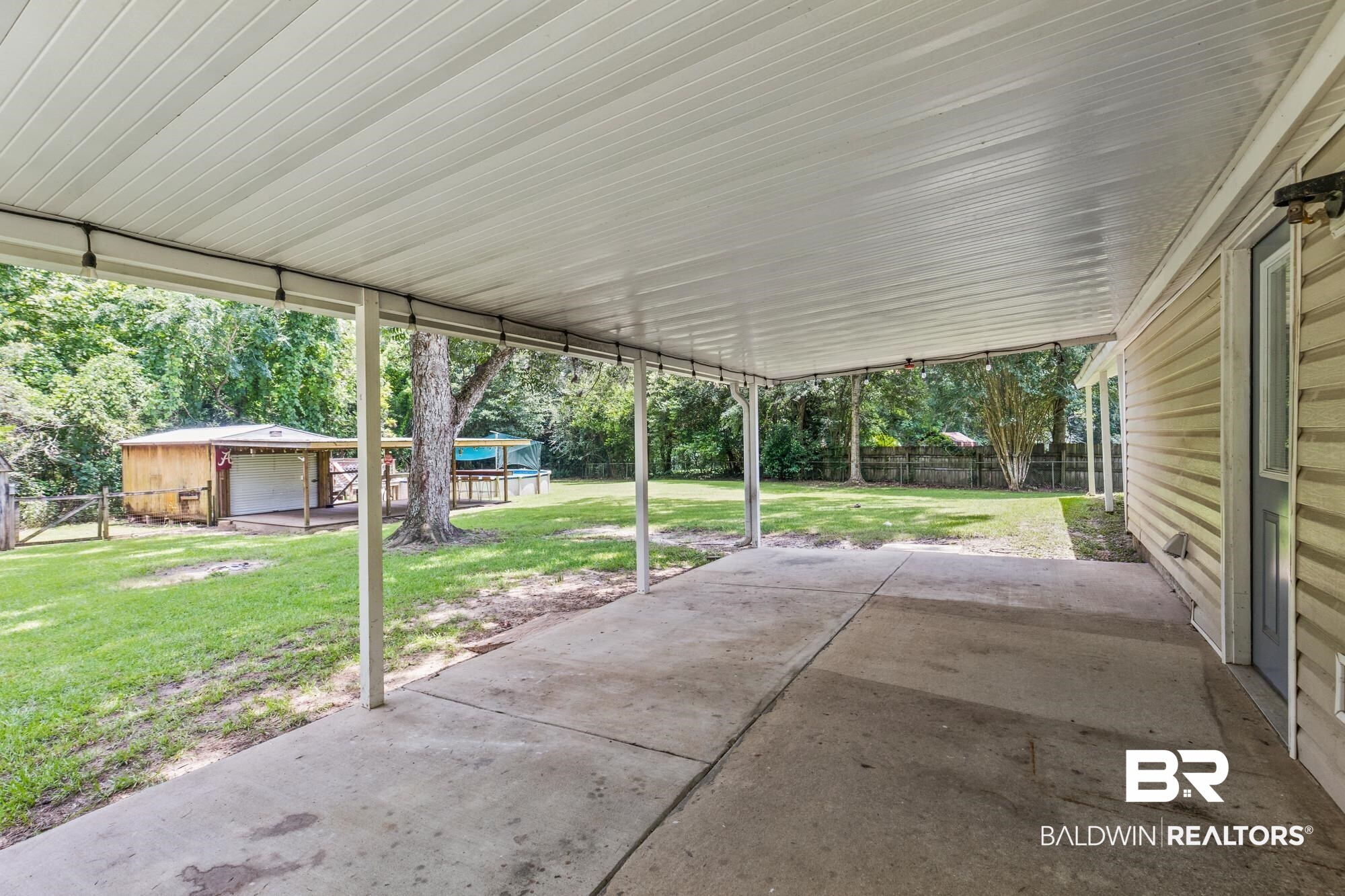 6933 Burbank Court Mobile, AL 36619 - Photo 22 of 25 Expansive covered patio featuring a concrete surface, white corrugated roof, and string lighting
