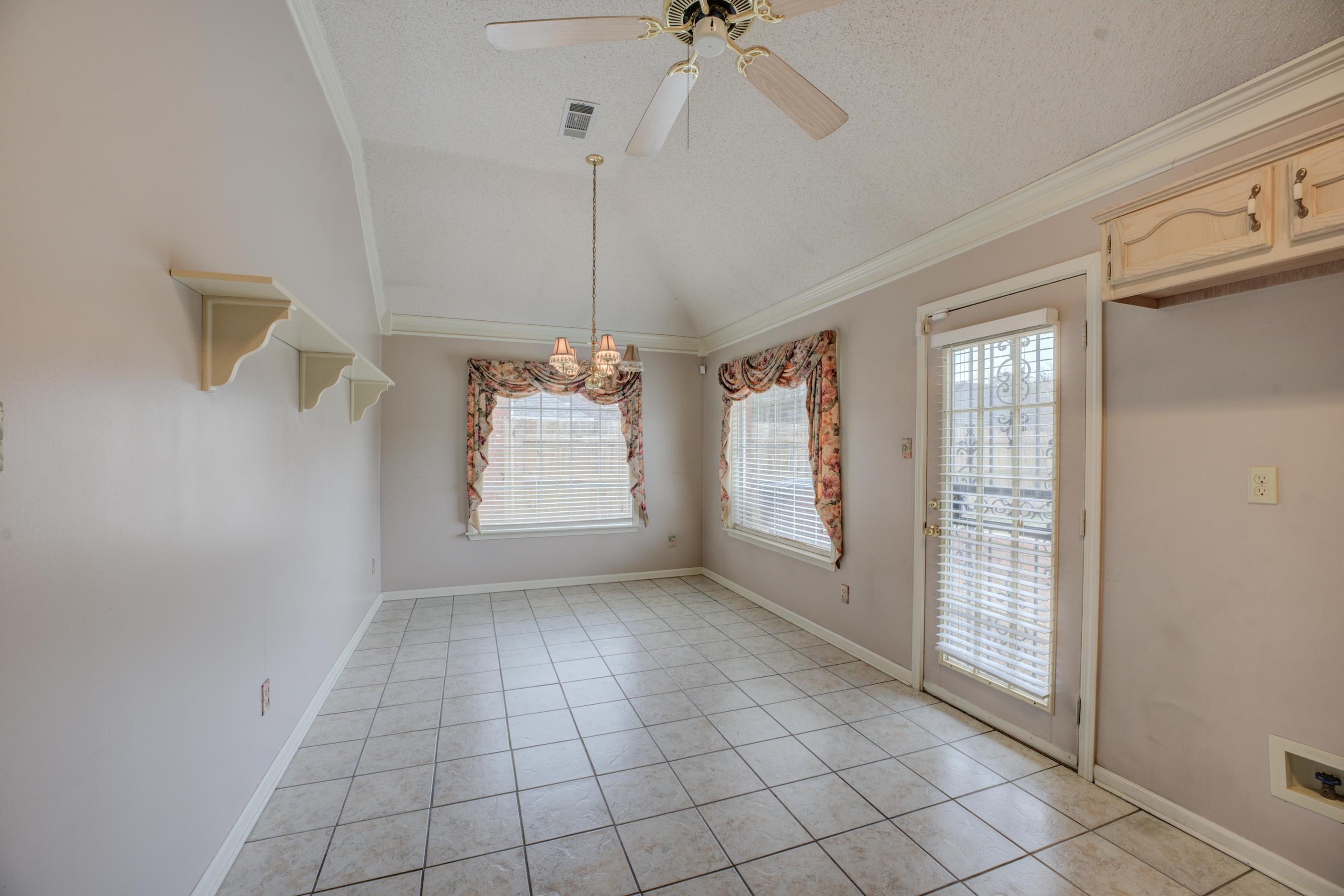 7657 Stone Manor Road Memphis, TN 38125 - Photo 11 of 27 Unfurnished dining area featuring ceiling fan with notable chandelier, a textured ceiling, light tile patterned floors, crown molding, and vaulted ceiling
