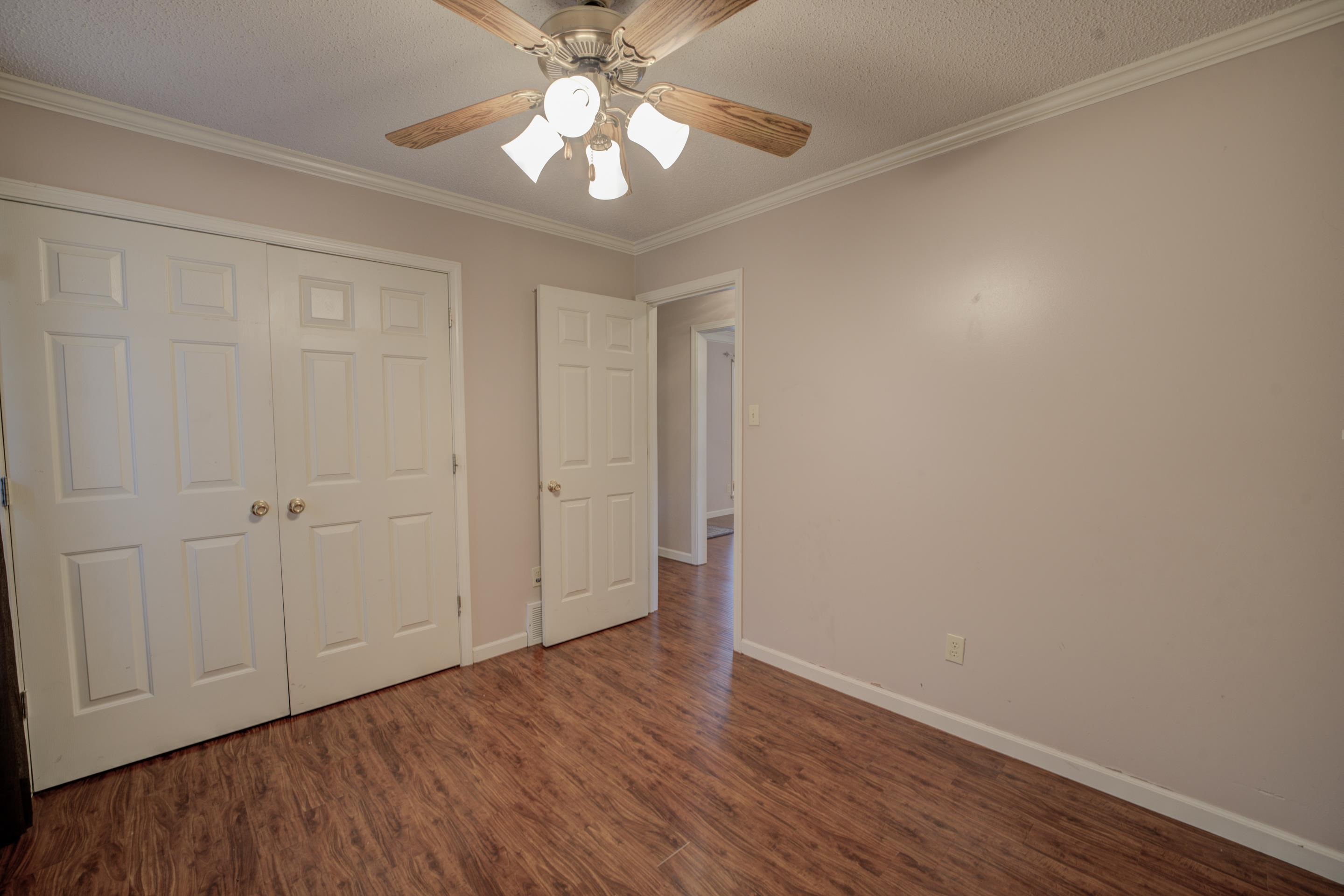 7657 Stone Manor Road Memphis, TN 38125 - Photo 17 of 27 Unfurnished bedroom with wood-type flooring, a textured ceiling, ornamental molding, ceiling fan, and a closet