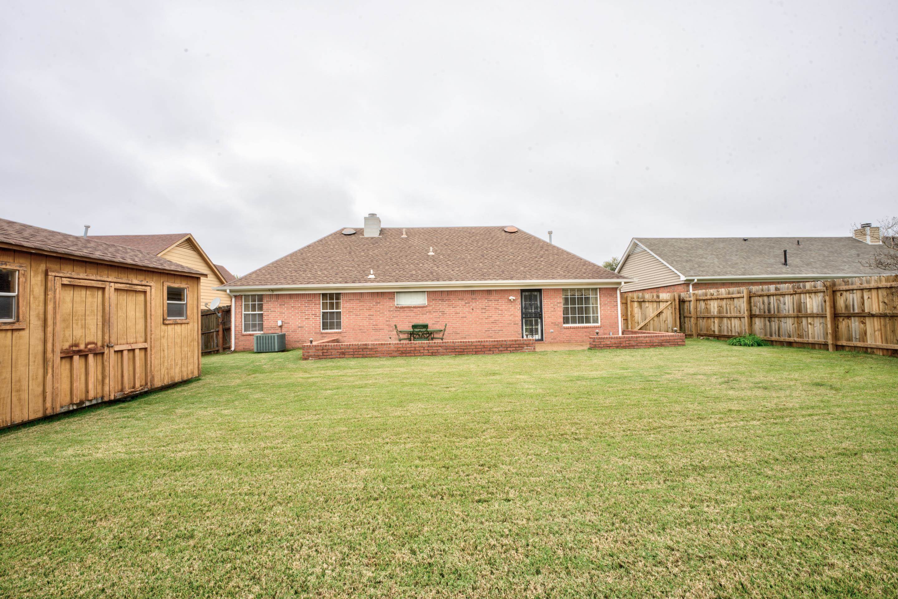 7657 Stone Manor Road Memphis, TN 38125 - Photo 24 of 27 Back of property with a lawn, a patio, central air condition unit, and a storage shed