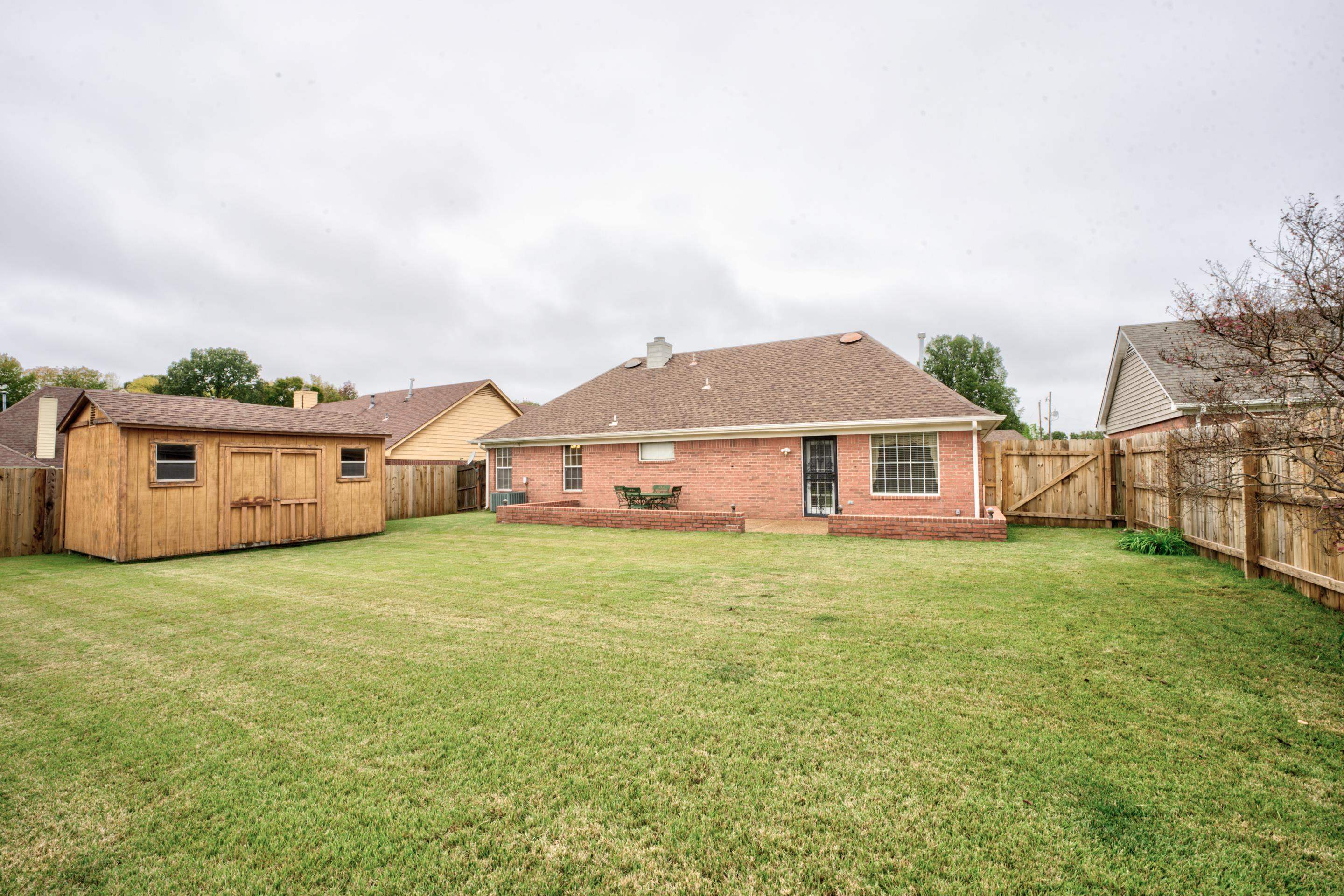 7657 Stone Manor Road Memphis, TN 38125 - Photo 25 of 27 Rear view of house with a patio, a yard, and a storage unit
