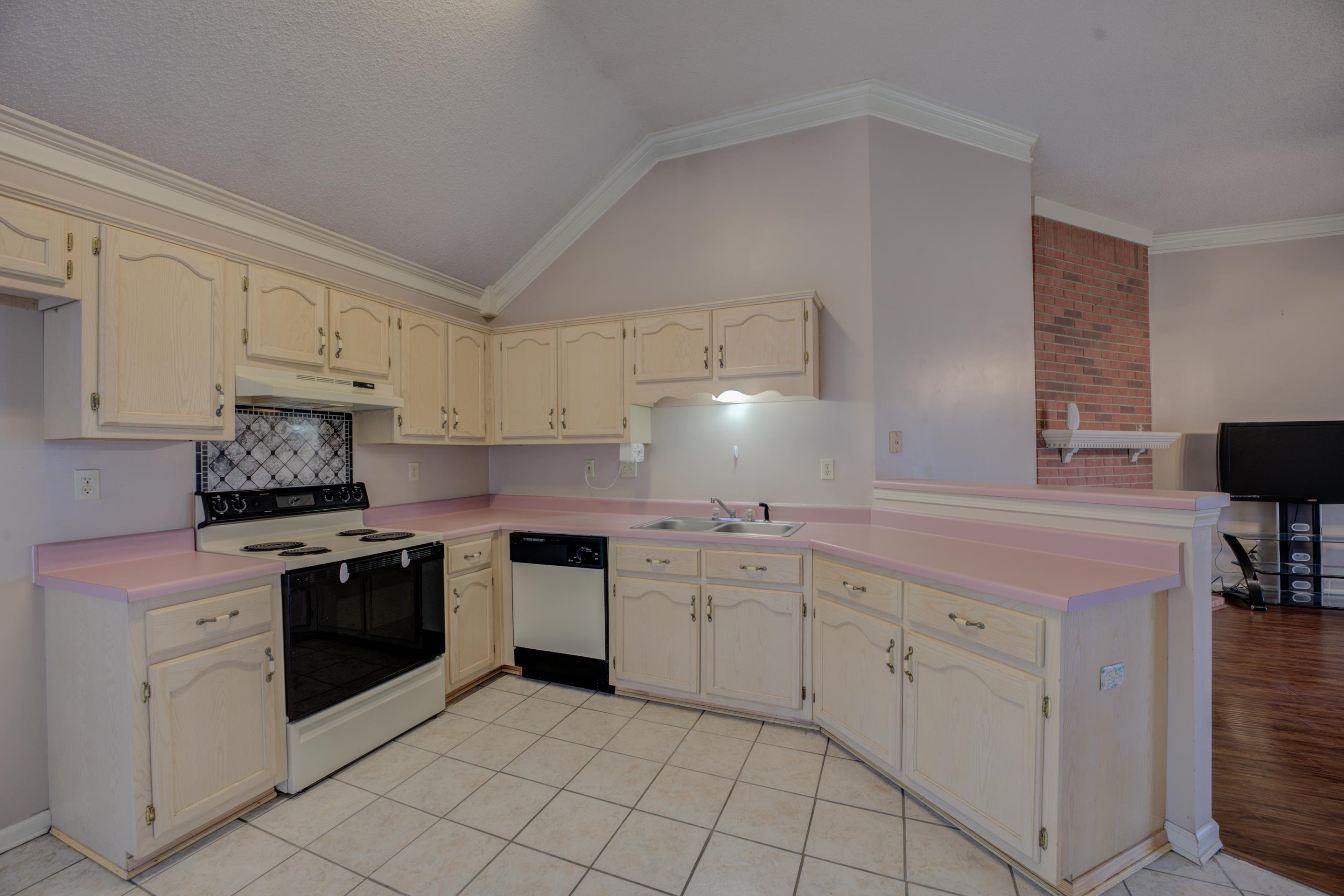 7657 Stone Manor Road Memphis, TN 38125 - Photo 9 of 27 Kitchen featuring ornamental molding, sink, vaulted ceiling, white appliances, and cream cabinetry
