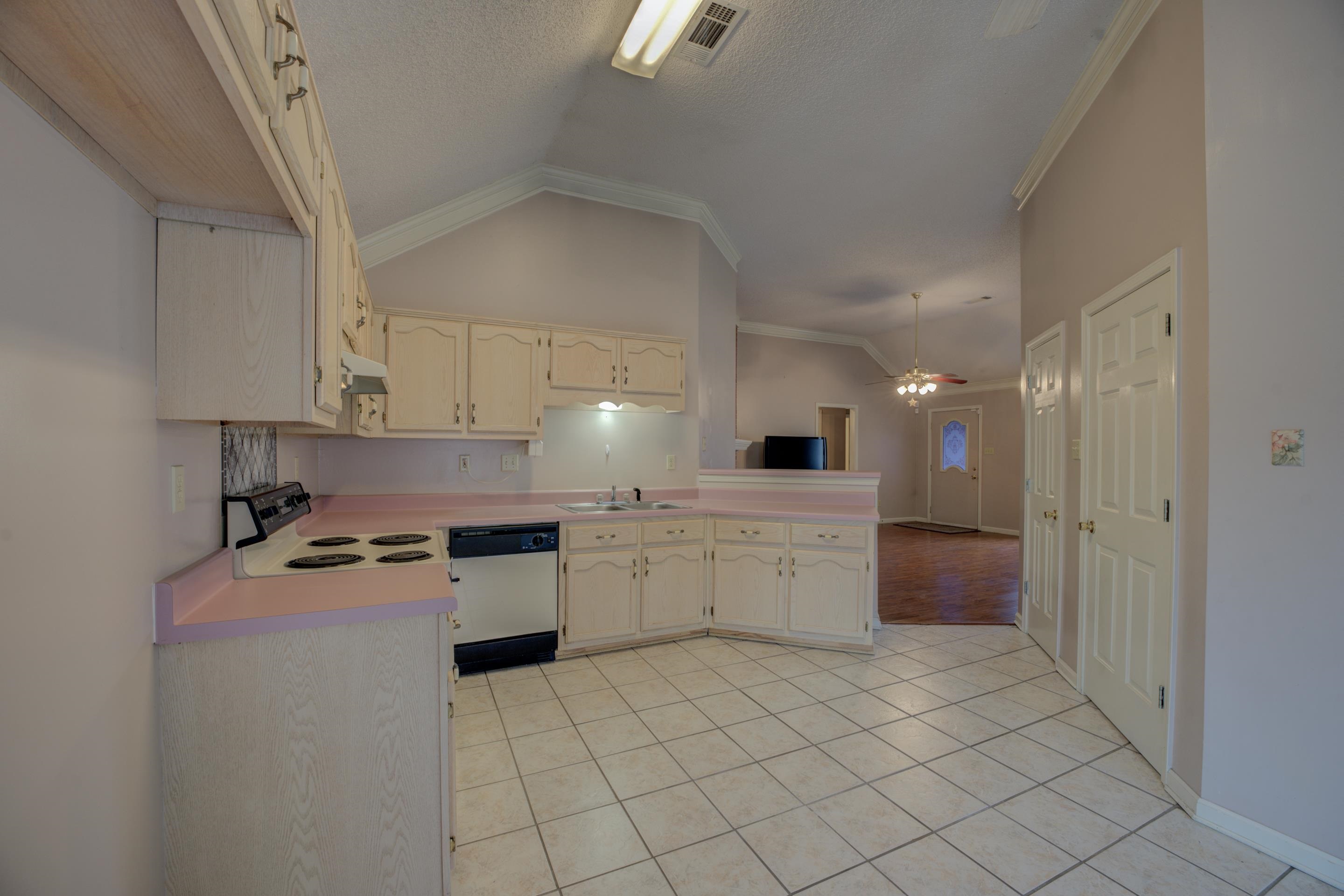 7657 Stone Manor Road Memphis, TN 38125 - Photo 10 of 27 Kitchen with ornamental molding, light tile patterned floors, range, lofted ceiling, and dishwasher