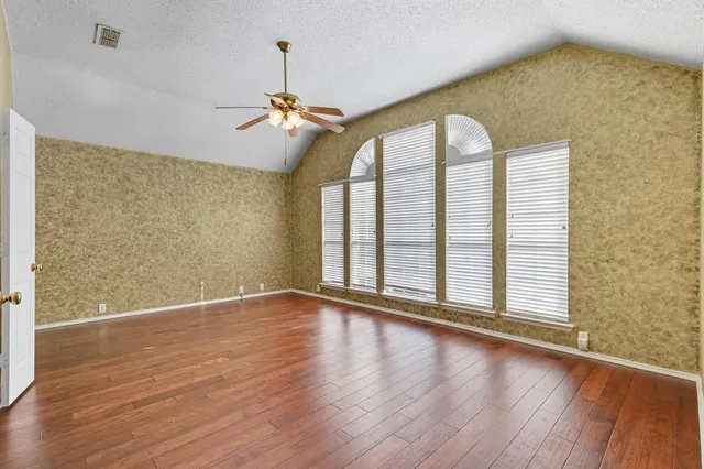 a view of an empty room with a window and wooden floor