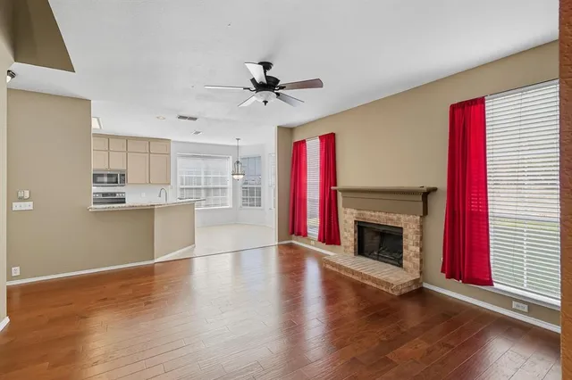 a view of a kitchen with a ceiling fan a fireplace and wooden floor