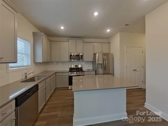 a kitchen with stainless steel appliances granite countertop a stove a sink and a refrigerator