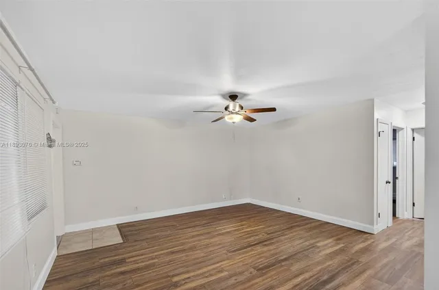 a view of a room with wooden floor and a ceiling fan