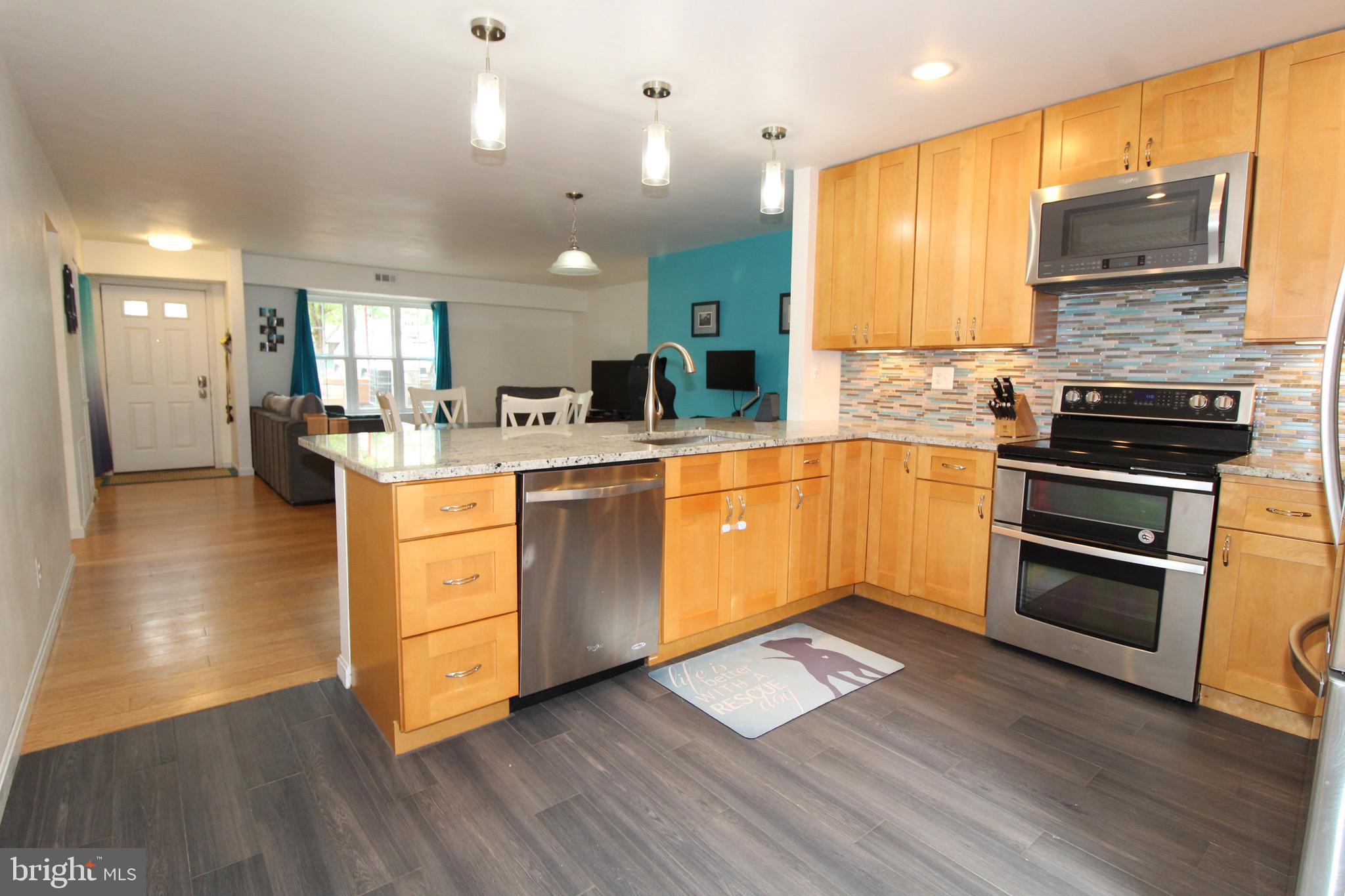 a kitchen with stainless steel appliances granite countertop a sink cabinets and wooden floor