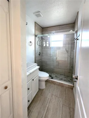a bathroom with a granite countertop shower a toilet and a shower